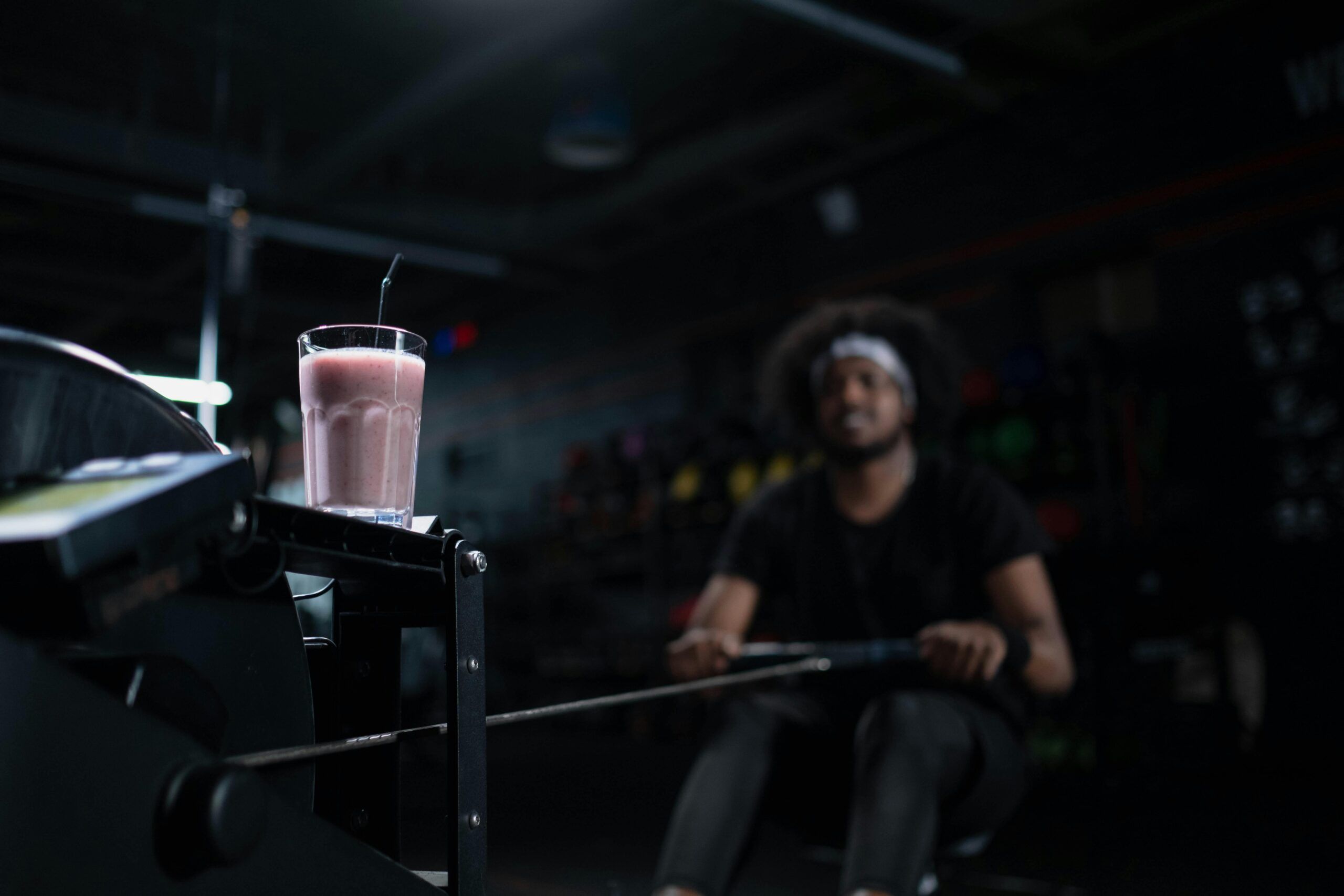 man-using-rowing-machine-with-sports-nutrition-shake-in-foreground